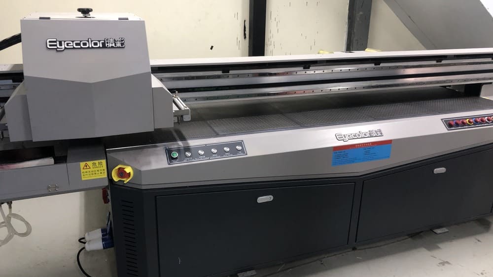 Công nghệ máy in UV phẳng là Khám Phá Công Nghệ Máy In UV Phẳng – In Ấn Trên Mọi Chất Liệugiải pháp in ấn hiện đại sử dụng mực in được làm khô tức thì bằng tia cực tím (UV), cho phép in trực tiếp lên hầu hết các bề mặt phẳng cứng và mềm như gỗ, kính, kim loại, mica, nhựa và da. Công nghệ này mang lại bản in sắc nét, bền màu, chống trầy xước và tiết kiệm thời gian, mở ra nhiều ứng dụng trong sản xuất quảng cáo, quà tặng, nội thất và nhiều lĩnh vực khác. Hãy cùng Khám Phá Công Nghệ Máy In UV Phẳng – In Ấn Trên Mọi Chất Liệu với bài viết này! Mục Lục Công Nghệ Máy In UV Phẳng Là Gì? Ứng Dụng Đa Dạng Của Máy In UV Phẳng - In Ấn Trên Mọi Chất Liệu Các Loại Máy In UV Phẳng Phổ Biến Hiện Nay Hướng Dẫn Cách Lựa Chọn Máy In UV Phẳng Phù Hợp Bí Quyết Vận Hành Và Bảo Dưỡng Máy In UV Phẳng Hiệu Quả (HowTo) So Sánh Máy In UV Phẳng Và Các Công Nghệ In Khác Những Câu Hỏi Thường Gặp Về Máy In UV Phẳng (FAQPage) Công Nghệ Máy In UV Phẳng Là Gì? Bạn đã bao giờ tự hỏi làm thế nào để in một hình ảnh sắc nét lên một tấm kính, một miếng gỗ hay thậm chí là một chiếc ốp lưng điện thoại chưa? Câu trả lời nằm ở công nghệ máy in UV phẳng. Đây là một trong những bước tiến đột phá nhất trong ngành in ấn kỹ thuật số hiện nay, để chúng tôi giúp bạn khám Phá Công Nghệ Máy In UV Phẳng – In Ấn Trên Mọi Chất Liệu. Máy in UV phẳng hoạt động như thế nào? Nguyên lý hoạt động của máy in UV phẳng rất đơn giản nhưng cực kỳ hiệu quả. Thay vì sử dụng nhiệt để làm khô mực như các loại máy in truyền thống, máy in UV phẳng lại dùng tia cực tím (UV) để làm khô mực ngay lập tức sau khi mực được phun ra. Phun mực: Máy in sẽ phun những giọt mực UV siêu nhỏ lên bề mặt vật liệu cần in. Chiếu đèn UV: Ngay sau khi mực được phun, đèn LED UV gắn trên đầu phun sẽ chiếu sáng. Năng lượng từ tia UV sẽ làm mực "đóng rắn" hay "đông đặc" ngay lập tức. Bám dính tuyệt vời: Lớp mực khô cứng này sẽ tạo thành một lớp màng chắc chắn, bám chặt vào vật liệu, không bị nhòe hay phai màu. Những ưu điểm vượt trội của máy in UV phẳng Máy in UV phẳng không chỉ là một thiết bị, nó là một giải pháp toàn diện mang lại nhiều lợi ích cho các doanh nghiệp in ấn. In trên mọi chất liệu: Đây là điểm mạnh nhất của công nghệ này. Bạn có thể in trên gỗ, kính, kim loại, nhựa PVC, mica, da, gạch men, và nhiều vật liệu khác mà các máy in thông thường không làm được. Độ bền cao: Bản in UV có khả năng chống nước, chống trầy xước, chống phai màu dưới tác động của ánh nắng mặt trời. Nhờ đó, sản phẩm có thể sử dụng ngoài trời trong thời gian dài mà vẫn giữ được chất lượng. Màu sắc sống động, chân thực: Mực UV có dải màu rộng, giúp tái tạo hình ảnh với độ phân giải cao và màu sắc rực rỡ. Tiết kiệm thời gian và thân thiện môi trường: Quá trình làm khô tức thì giúp rút ngắn thời gian sản xuất. Mực UV không chứa dung môi, ít mùi, an toàn hơn cho người sử dụng và môi trường. Ứng Dụng Đa Dạng Của Máy In UV Phẳng - In Ấn Trên Mọi Chất Liệu Khi đã Khám Phá Công Nghệ Máy In UV Phẳng – In Ấn Trên Mọi Chất Liệu và hiểu về công nghệ máy in UV phẳng, bạn sẽ thấy nó được ứng dụng rộng rãi như thế nào trong đời sống và kinh doanh. Ngành quảng cáo và trang trí: In logo, hình ảnh lên bảng hiệu, biển quảng cáo bằng mica, alu. Tạo các sản phẩm POSM độc đáo. Làm decal 3D nổi bật. Ngành quà tặng và lưu niệm: In hình ảnh lên ốp lưng điện thoại, bật lửa, sạc dự phòng. Làm kỷ niệm chương, huy chương bằng kim loại, gỗ. In lên các sản phẩm cá nhân hóa như sổ tay, bút viết, ví da. Ngành nội thất và xây dựng: In tranh gạch 3D, ốp tường, ốp trần. Tạo điểm nhấn cho đồ nội thất bằng gỗ, kính. In hoa văn lên kính, đá tự nhiên để trang trí. Các ứng dụng này chỉ là một phần nhỏ, máy in UV phẳng còn có thể mở rộng ra nhiều lĩnh vực khác, từ in tem nhãn, in bao bì sản phẩm cho đến in mạch điện tử. Các Loại Máy In UV Phẳng Phổ Biến Hiện Nay Trên thị trường, có rất nhiều loại máy in UV phẳng khác nhau, đáp ứng mọi nhu cầu từ kinh doanh nhỏ lẻ đến sản xuất công nghiệp. Khám Phá Công Nghệ Máy In UV Phẳng – In Ấn Trên Mọi Chất Liệu với các cách phân loại cơ bản sau: Phân loại theo kích thước khổ in: Máy in UV phẳng khổ nhỏ (A4, A3): Phù hợp cho các cửa hàng dịch vụ in lấy ngay, sản xuất quà tặng cá nhân hóa với số lượng nhỏ. Máy in UV phẳng khổ trung (1.3m x 2.5m): Thường được sử dụng trong các xưởng in quảng cáo, làm nội thất vừa và nhỏ. Máy in UV phẳng khổ lớn (trên 2.5m): Dành cho các công ty in ấn chuyên nghiệp, sản xuất các tấm vật liệu lớn như gạch ốp, kính cường lực, hoặc các sản phẩm công nghiệp. Phân loại theo thương hiệu: Thương hiệu quốc tế: Các hãng nổi tiếng như Mimaki (Nhật Bản), Mutoh (Nhật Bản), Agfa (Bỉ),... mang lại chất lượng và độ bền cao. Thương hiệu nội địa: Các dòng máy lắp ráp trong nước hoặc nhập khẩu từ Trung Quốc có giá thành hợp lý hơn, phù hợp với các doanh nghiệp khởi nghiệp. Hướng Dẫn Cách Lựa Chọn Máy In UV Phẳng Phù Hợp Việc đầu tư vào một chiếc máy in UV phẳng là một quyết định lớn. Dưới đây là những tiêu chí quan trọng bạn cần Khám Phá Công Nghệ Máy In UV Phẳng – In Ấn Trên Mọi Chất Liệu trước khi đưa ra lựa chọn. Xác định nhu cầu kinh doanh: Bạn sẽ in trên chất liệu gì là chính? (Gỗ, kính, da,...) Kích thước sản phẩm bạn thường làm là bao nhiêu? Bạn cần tốc độ in nhanh hay chất lượng in siêu cao? Ngân sách đầu tư: Máy in UV phẳng có giá đa dạng, từ vài chục triệu đến hàng tỷ đồng. Hãy xác định ngân sách để khoanh vùng lựa chọn. Cần tính toán cả chi phí vận hành, bảo dưỡng, mực in và vật tư tiêu hao. Công suất và tốc độ: Đối với sản xuất hàng loạt, bạn nên chọn máy có tốc độ và công suất cao. Đối với dịch vụ in lẻ, một chiếc máy khổ nhỏ với tốc độ vừa phải là đủ. Chính sách bảo hành và sửa chữa máy in: Hãy tìm kiếm nhà cung cấp uy tín, có đội ngũ kỹ thuật lành nghề, cung cấp dịch vụ bảo hành, bảo trì và sửa chữa máy in chuyên nghiệp. Điều này cực kỳ quan trọng vì máy in là thiết bị kỹ thuật, có thể gặp sự cố bất cứ lúc nào. Bí Quyết Vận Hành Và Bảo Dưỡng Máy In UV Phẳng Hiệu Quả (HowTo) Để đảm bảo máy in UV phẳng của bạn hoạt động ổn định và bền bỉ, bạn cần tuân thủ các quy trình vận hành và bảo dưỡng đúng cách. Khám Phá Công Nghệ Máy In UV Phẳng – In Ấn Trên Mọi Chất Liệu với quy trình cơ bản tham khảo: Quy trình vận hành máy in UV phẳng: Kiểm tra tổng quan: Trước mỗi lần in, hãy kiểm tra mực in, đầu phun, đèn UV và các bộ phận cơ học khác. Chuẩn bị vật liệu: Đặt vật liệu cần in lên mặt bàn in phẳng, cố định chắc chắn để tránh xê dịch trong quá trình in. Cài đặt phần mềm: Mở file thiết kế trên máy tính, sử dụng phần mềm RIP để cài đặt các thông số như độ phân giải, chế độ màu, và tốc độ in. Bắt đầu in: Nhấn nút lệnh và theo dõi quá trình máy in hoạt động. Sau khi hoàn thành, lấy sản phẩm ra và xử lý. Cách bảo dưỡng và vệ sinh máy in: Vệ sinh đầu phun hàng ngày: Sử dụng dung dịch vệ sinh chuyên dụng để lau chùi nhẹ nhàng đầu phun. Việc này giúp ngăn ngừa mực khô làm tắc nghẽn đầu phun. Vệ sinh hệ thống mực: Kiểm tra và làm sạch các ống dẫn mực, bộ lọc mực để đảm bảo mực được lưu thông thông suốt. Bảo quản máy: Đặt máy ở nơi khô ráo, thoáng mát, tránh ánh nắng trực tiếp và bụi bẩn. Khi không sử dụng, hãy che chắn máy cẩn thận. So Sánh Máy In UV Phẳng Và Các Công Nghệ In Khác Để thấy được sự vượt trội của công nghệ máy in UV phẳng, Khám Phá Công Nghệ Máy In UV Phẳng – In Ấn Trên Mọi Chất Liệu hãy so sánh nó với một số công nghệ in phổ biến khác. In UV phẳng vs. In decal dán: Thay vì phải in lên decal rồi dán thủ công lên sản phẩm, in UV phẳng cho phép in trực tiếp. Điều này giúp tiết kiệm thời gian, tăng độ bền và tính thẩm mỹ cho sản phẩm. In UV phẳng vs. In mực dung môi: Mực dung môi chứa nhiều hóa chất độc hại, có mùi nồng, dễ bay màu và kén vật liệu. Ngược lại, mực UV an toàn hơn, bền hơn và in được trên nhiều bề mặt hơn. Những Câu Hỏi Thường Gặp Về Máy In UV Phẳng (FAQPage) Dưới đây là một số câu hỏi thường gặp mà các khách hàng quan tâm đến máy in UV phẳng thường đặt ra, vậy để hiểu rõ hơn hãy cùng đặt ra một vài câu hỏi cần thiết khi Khám Phá Công Nghệ Máy In UV Phẳng – In Ấn Trên Mọi Chất Liệu: Chi phí đầu tư ban đầu cho máy in UV phẳng có cao không? Chi phí đầu tư ban đầu cho một chiếc máy in UV phẳng có thể từ vài chục đến hàng trăm triệu đồng, tùy thuộc vào công suất, kích thước và thương hiệu. Tuy nhiên, khả năng sinh lời và đa dạng hóa sản phẩm mà nó mang lại thường rất lớn. Máy in UV phẳng có dễ sử dụng không? Hầu hết các dòng máy hiện đại đều có phần mềm điều khiển thân thiện với người dùng. Các nhà cung cấp uy tín cũng sẽ có chương trình đào tạo kỹ thuật cho khách hàng. Vật tư tiêu hao (mực, đầu phun) có đắt không? Mực in UV và đầu phun là hai vật tư tiêu hao chính. Chi phí có thể cao hơn mực thông thường, nhưng với độ bền của bản in, nó lại tiết kiệm chi phí lâu dài cho việc in đi in lại sản phẩm. Có cần phải sửa chữa máy in UV phẳng thường xuyên không? Với việc bảo dưỡng định kỳ và vận hành đúng cách, máy in sẽ rất bền bỉ. Tuy nhiên, việc sửa chữa máy in là không thể tránh khỏi. Vì vậy, hãy chọn nhà cung cấp có dịch vụ hỗ trợ kỹ thuật tốt. Máy in UV phẳng có in được vật liệu cuộn không? Có, một số dòng máy UV phẳng có thêm tùy chọn cuộn để in được các vật liệu mềm như da, bạt, decal cuộn. Liên hệ ngay với chúng tôi để biết thêm thông tin Công nghệ máy in UV phẳng không chỉ là một thiết bị in ấn thông thường mà còn là một khoản đầu tư chiến lược cho mọi doanh nghiệp. Khả năng in trên đa dạng vật liệu cùng với chất lượng bản in bền đẹp, sắc nét đã mở ra vô số cơ hội kinh doanh mới. Việc lựa chọn một chiếc máy in UV phẳng phù hợp và duy trì bảo dưỡng đúng cách sẽ giúp bạn tối ưu hóa hiệu quả sản xuất và tạo ra lợi thế cạnh tranh mạnh mẽ trên thị trường. Chúng tôi luôn sẵn sàng cùng bạn Khám Phá Công Nghệ Máy In UV Phẳng – In Ấn Trên Mọi Chất Liệu